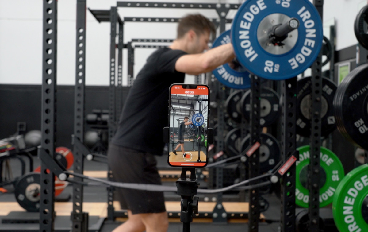 Lifter doing a back squat with a bar speed tracking app - Metric VBT in a tripod